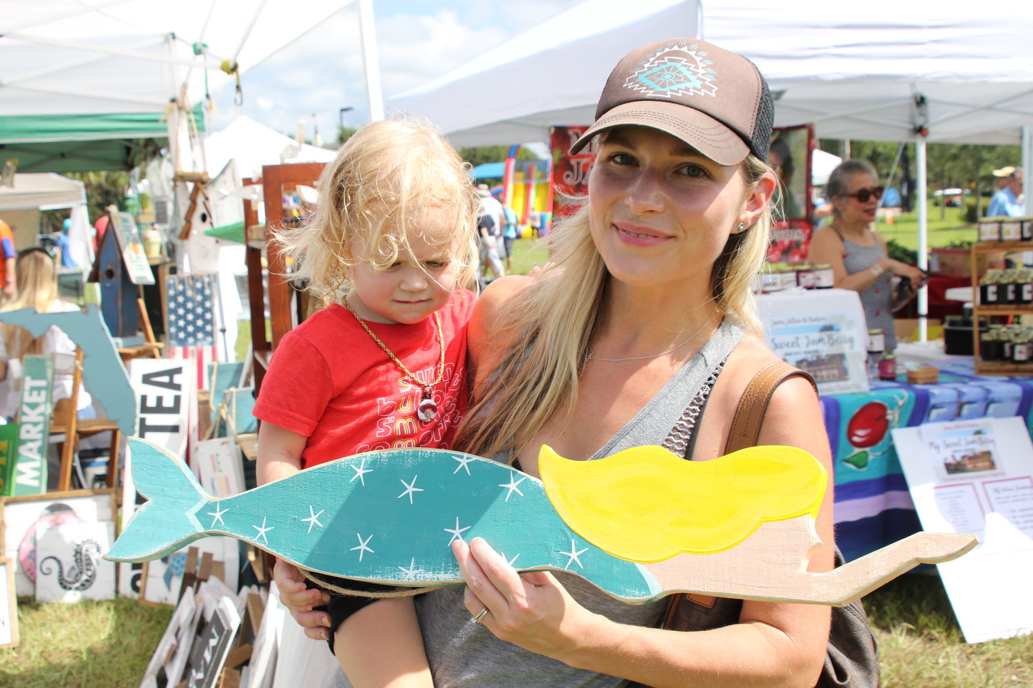Jordan Gamber holds daughter Ali and shows off mermaid art she purchased at the market.